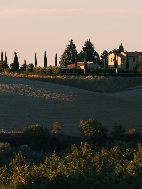 Tuscan farmhouse on rolling hills at sunset